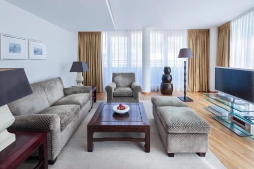 a living room with two couches and a tv at The Mandala Berlin, a Member of Design Hotels in Berlin