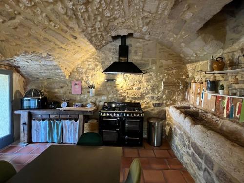 Il comprend une cuisine avec une cuisinière et un mur en pierre. dans l'établissement Ancienne Maison de Vigneron avec Jacuzzi - Uzès, à Sanilhac-et-Sagriès
