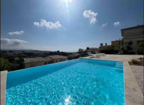 une grande piscine bleue devant une maison dans l'établissement DOMAINE LOU BEL AZUR - Harmonie, à Saint-Laurent-du-Var