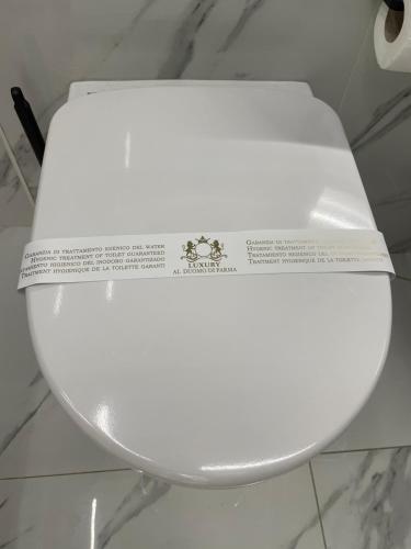 a white toilet with a sign on the top of it at Luxury 6 al duomo di parma in Parma