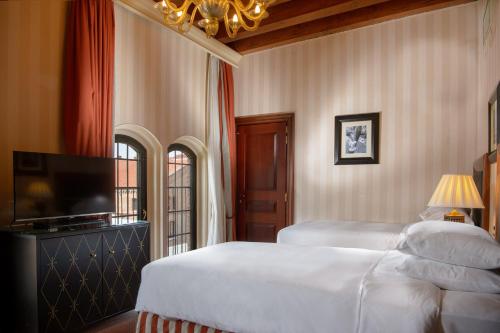 a bedroom with two beds and a flat screen tv at Hilton Molino Stucky Venice in Venice