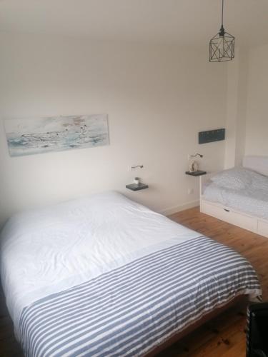 une chambre blanche avec un lit avec une couverture rayée dans l'établissement Maison le Tréport, à Woincourt