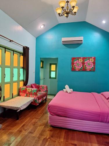 a bedroom with a pink bed and a blue wall at Baanrak amphawa homestay in Amphawa