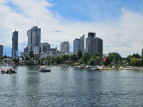 a river with boats in a city with buildings at Yuki's Place - UN-VIC, Danube Beach and Subway near to Downtown Vienna in Vienna