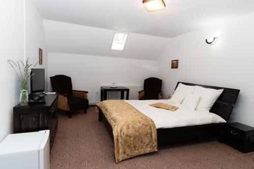 a bedroom with a bed and two chairs and a desk at Casa Stejarul Lui Andrei in Izvoarele
