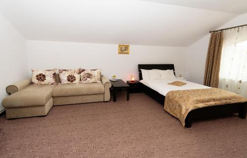 a hotel room with a bed and a couch at Casa Stejarul Lui Andrei in Izvoarele