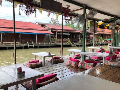 a deck with tables and chairs on the water at Baanrak amphawa homestay in Amphawa