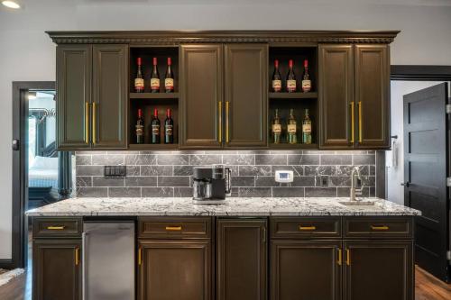 a kitchen with brown cabinets and bottles of wine at Entire Hermann Hideout in Hermann