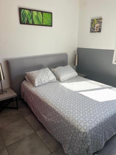 une chambre avec un lit avec des draps blancs et des oreillers dans l'établissement Appartement à 20 m de la plage, à Frontignan