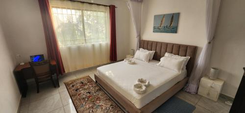 a bedroom with a bed with white sheets and a window at Villa Salaam in Diani Beach
