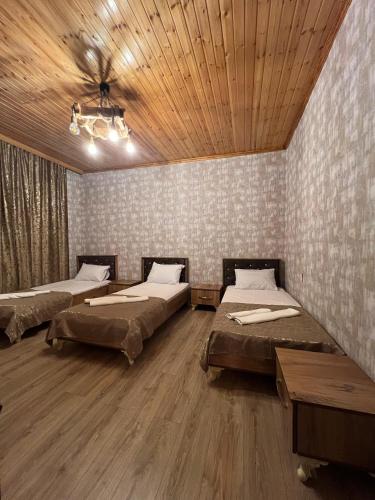 a room with three beds and a wooden ceiling at Cozy House with Swimming Pool near city center in Gabala