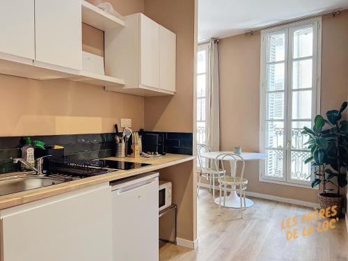 - une cuisine avec des placards blancs, un évier et une table dans l'établissement Magnifique Studio - Hyper Central & Climatisation - Les Frères de la Loc', à Marseille