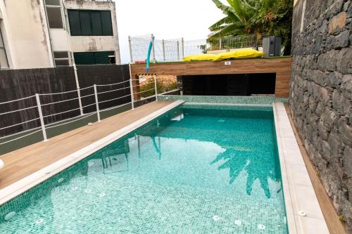 a swimming pool with blue water and a wooden deck at HOMELIKE FUNCHAL I in Funchal