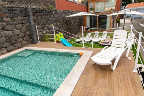 a swimming pool with white chairs and a swimming pool at HOMELIKE FUNCHAL I in Funchal