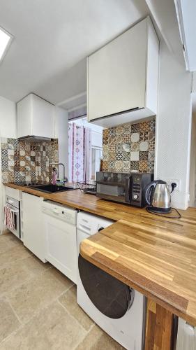 une cuisine avec des armoires blanches et un comptoir en bois dans l'établissement Appartement Boulogne-Billancourt, à Boulogne-Billancourt