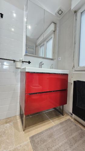 La salle de bains est pourvue d'un lavabo rouge et d'un miroir. dans l'établissement Appartement Boulogne-Billancourt, à Boulogne-Billancourt