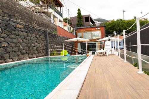 a swimming pool with a wooden deck and a building at HOMELIKE FUNCHAL I in Funchal