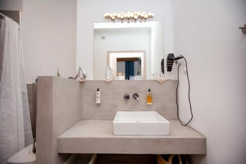 a bathroom with a sink and a mirror at T H E BERLIN Studios and Suites in Nea Vrasna