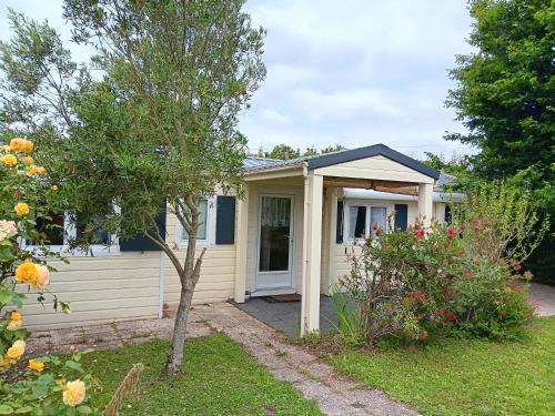 une petite maison jaune avec une véranda et un arbre dans l'établissement Chalet mer et campagne, à Bourgneuf-en-Retz