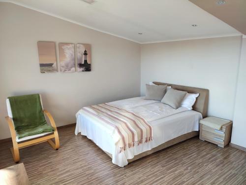 een slaapkamer met een bed en een groene stoel bij LUX Apartman in Balatonfüred