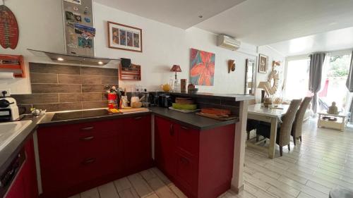 La cuisine est équipée de placards rouges, d'un évier et d'une table. dans l'établissement La Cabane en bord de mer Cavalaire sur mer, à Cavalaire-sur-Mer