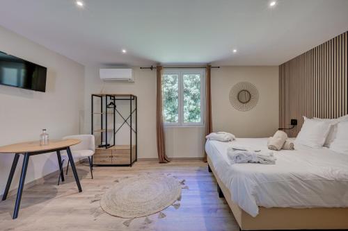 a bedroom with two beds and a table and a desk at Clos Saint-Michel Resort & Spa in Malaucène