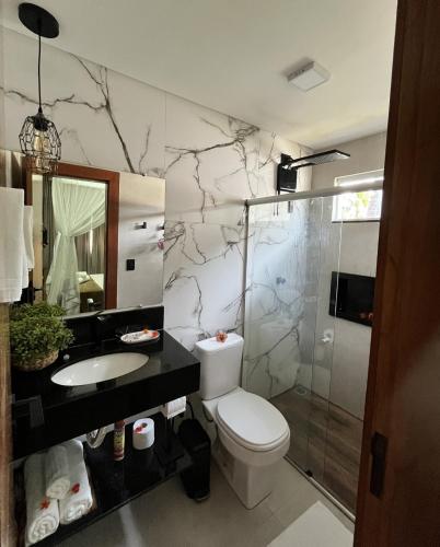 a bathroom with a toilet and a sink and a shower at Pousada Corumbau in Corumbau
