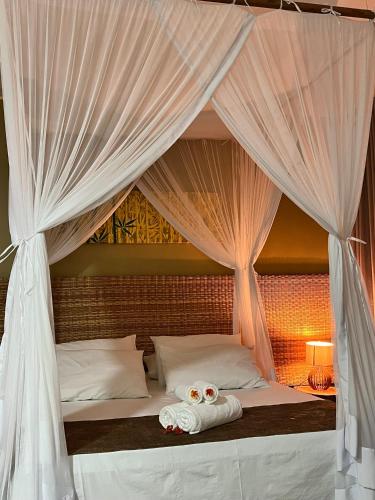 a bed with a canopy with two towels on it at Pousada Corumbau in Corumbau