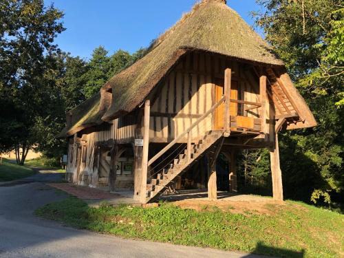 un grand bâtiment avec un toit de chaume avec un escalier dans l'établissement Les Noctam'bulles - Cabanes dans les arbres, à Saint-Pierre-Azif