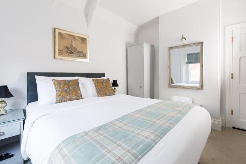 a white bedroom with a bed and a window at 4 Canon Lane in Chichester