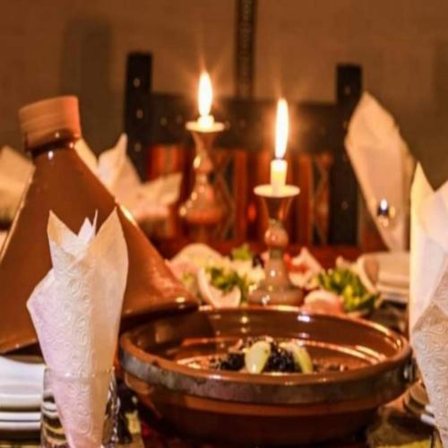 a table with a plate of food and two candles at Desert Paradise Luxury Camp in Merzouga