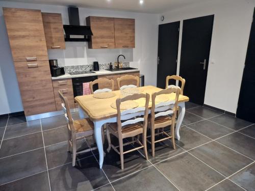 a kitchen with a dining room table and chairs at Le cottage champêtre in Escaudoeuvres