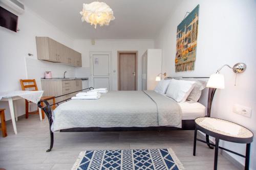 a bedroom with a bed and a table and a kitchen at T H E BERLIN Studios and Suites in Nea Vrasna