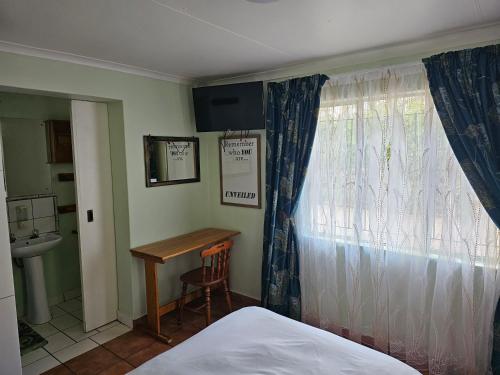 a bedroom with a bed and a desk and a window at King Sanctuary in Centurion