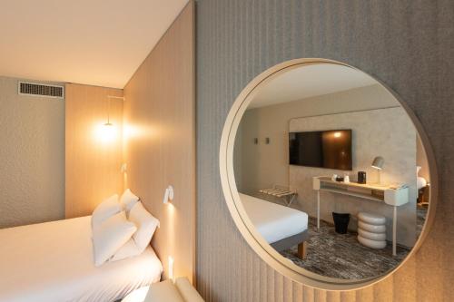 a hotel room with a bed and a mirror at Novotel Macon Nord - Porte de Bourgogne in Mâcon