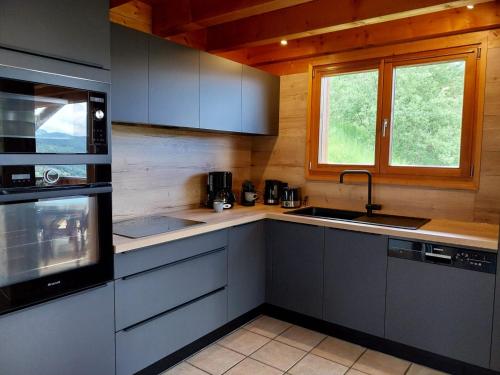 d'une cuisine avec des placards gris, un évier et une fenêtre. dans l'établissement Chalet individuel avec Wi-Fi, parking privé et animaux acceptés - FR-1-671-58, aux Gets
