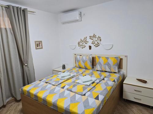 a bedroom with a bed with a yellow and gray comforter at Апартамент Морската Къща-НЕСТИНАРКА in Tsarevo