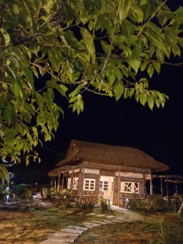 une maison avec un toit de chaume la nuit dans l'établissement K50 Waterfall Village - Homestay Măng Đen, à Kon Plong