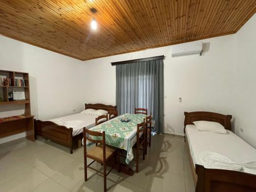 a room with two beds and a table and chairs at Guesthouse Dollomaja Ksamil in Ksamil