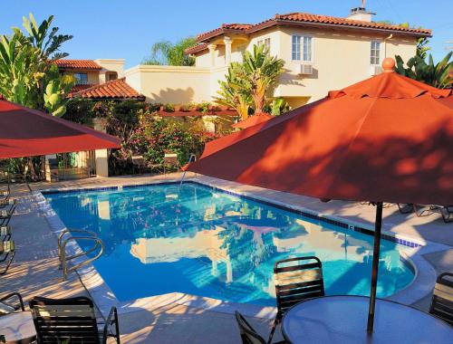 uma piscina com guarda-sol, mesas e cadeiras em Old Town Inn em San Diego