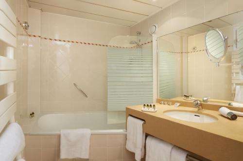 a bathroom with a tub and a sink and a mirror at Relais Du Louvre in Paris