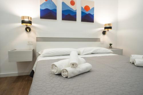 a white bedroom with two towels on a bed at Vela Rossa Deluxe Apartment in Trapani