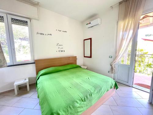 a bedroom with a green bed in a room with windows at Pineta Apartament in Tirrenia