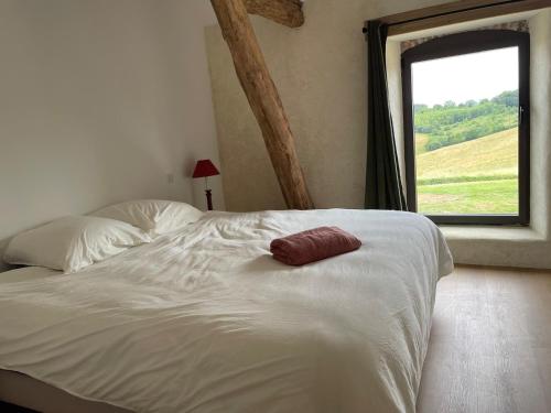 a white bed with a red pillow on top of it at Laborde in Monpardiac