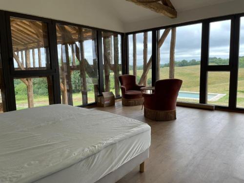 a bedroom with a bed and some chairs and windows at Laborde in Monpardiac