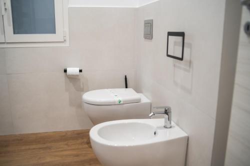 a white bathroom with a toilet and a sink at Vela Rossa Deluxe Apartment in Trapani