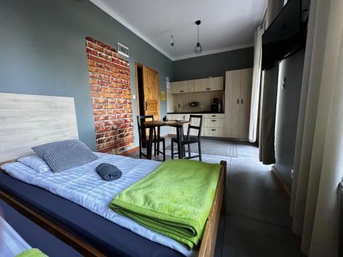 a bedroom with a bed with a green blanket on it at Apartamenty Rycerskie in Inowłódz