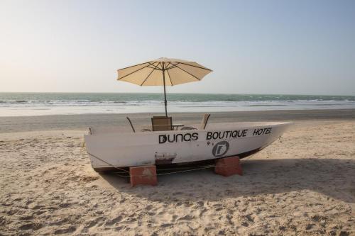 a boat sitting on the beach with an umbrella at Dunas Boutique Hotel in Kololi