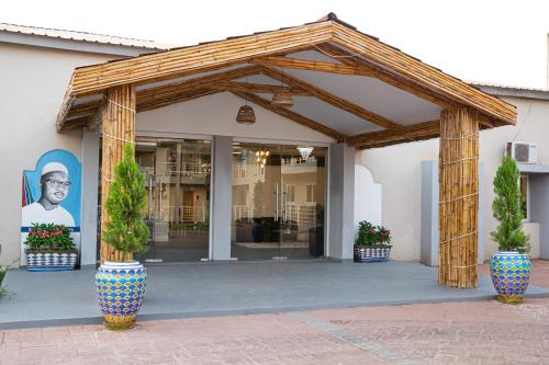 a wooden pavilion with potted plants in front of a building at Dunas Boutique Hotel in Kololi