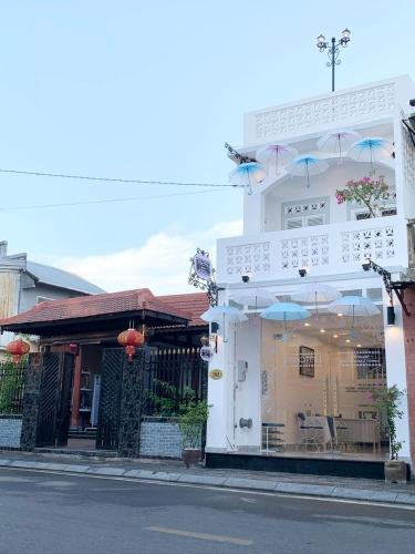 a white building with a window with chairs and umbrellas at Timothy House Hue in Hue